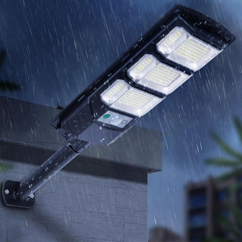 JUDYSSY Outdoor Waterproof Solar Street Light Led Wall Light installed on a wall, illuminated in the rain, outdoor setting.