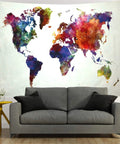 Colorful watercolor world map tapestry for home and classroom above a grey sofa, educational wall decor on lightweight polyester.