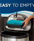 Hand holding the teal dust bin of the Super Lightweight Cordless Floor Sweeper for easy disposal in a trash can.