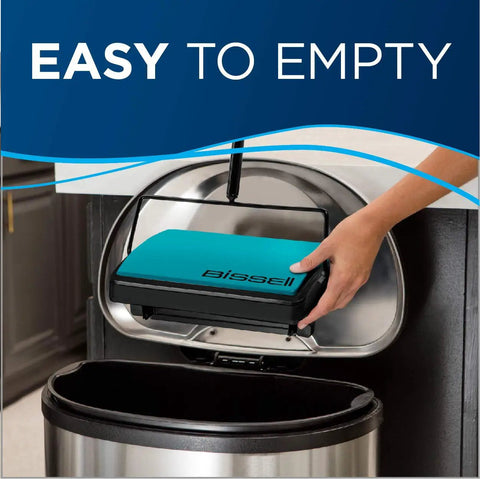 Hand holding the teal dust bin of the Super Lightweight Cordless Floor Sweeper for easy disposal in a trash can.