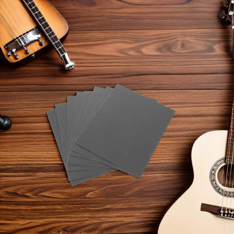 Guitar Fretboard Protector Kit With Metal Fretboard Guards And Sandpaper Sheets For Precision Smoothing And Safe Fret Maintenance And Repair Includes Durable Metal Shields And Fine Polishing Papers For Clean Edges And Pro Grade Guitar Care. metal guards and sanding sheets on wood table
