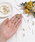 Hand displaying gold torsion springs and screws from Hair Claw Clip Spring Replacement Kit 40 Sets Of Gold Torsion Springs With Screws DIY Repair And Craft Gear For Quick Fixes Easy Clip Makeovers Pro Level Results For Crafts next to decorative objects.