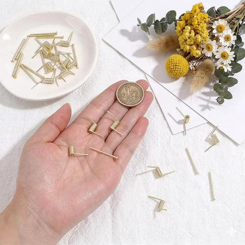 Hand displaying gold torsion springs and screws from Hair Claw Clip Spring Replacement Kit 40 Sets Of Gold Torsion Springs With Screws DIY Repair And Craft Gear For Quick Fixes Easy Clip Makeovers Pro Level Results For Crafts next to decorative objects.
