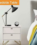 Modern bedside table with drawers, black lamp, and clock next to a bed with colorful bedding.