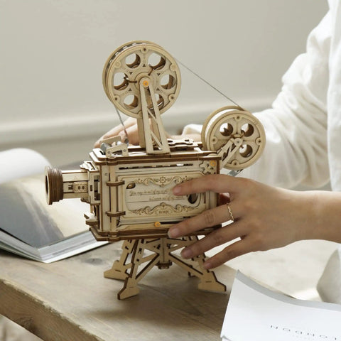 Hand assembling Vitascope 3D Wooden Puzzle Kit For Adults, Mechanical Model Building Set on a desk, close-up view.