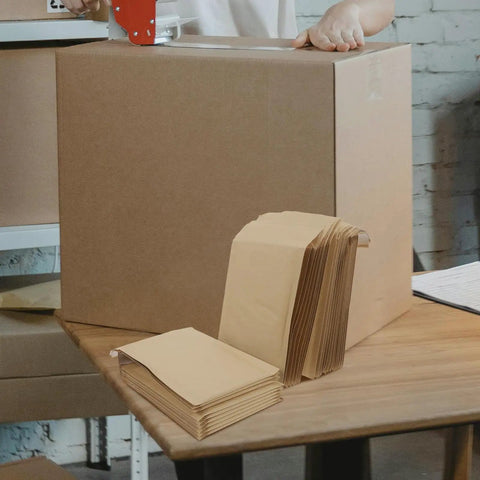 Khaki Padded Mailing Envelopes 22x34cm, 20 Pack Bubble Mailers on packing table next to sealed box in warehouse