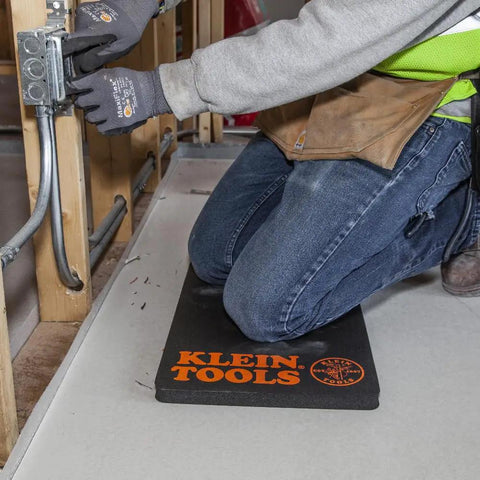 Tradesman kneeling on 1-inch thick NBR foam knee pad with handle, providing ultimate knee protection and comfort on job site