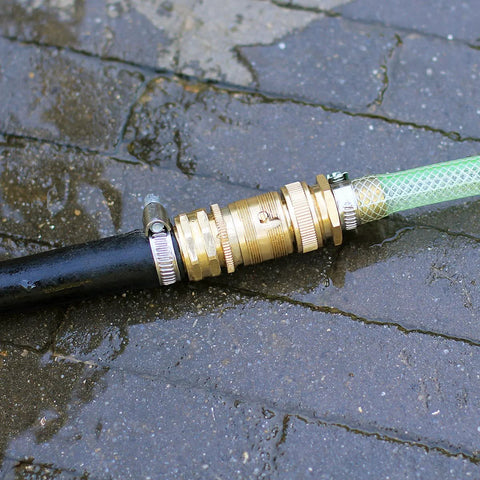 Installed solid-brass 3/4-inch GHT garden hose quick-connect fitting joining black and green hoses.