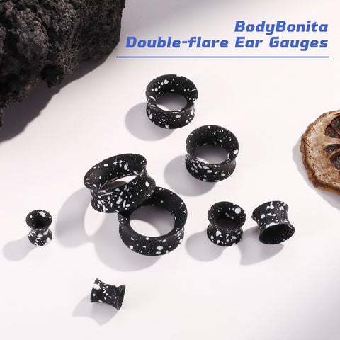 Silicone Ear Gauges 00G Double Flared Plugs Set for Ear Stretching, black with white speckles, laid out on white surface.