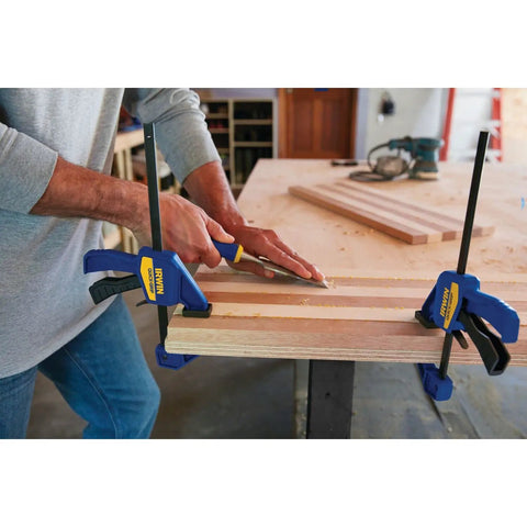 Six Inch Mini Bar Clamp Two Pack With One Hand Quick Release Trigger Rock Solid Grip Non Marring Pads in use on wood.