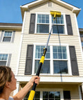Person using Heavy-Duty Commercial Extension Pole Delivers 4.5 To 18 Ft Reach For True Two-Story Access Up To 24 Ft Total on house exterior.