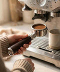 54mm Bottomless Espresso Portafilter With Three Ear Design For Breville And Sage Barista Machines in hand near espresso machine.