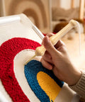Person using adjustable punch needle embroidery kit for beginners and adults with wooden handle on colorful fabric.