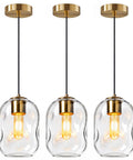 3 Pack Gold Pendant Lights For Kitchen Island Featuring 8.7 Inch Hand Blown Clear Art Glass Globes hanging above a kitchen island.