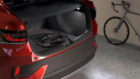 Portable EV Charger With 12 Amp Output, 25 Ft Rugged Cable in car trunk; SAE J1772 Connector, Indoor Outdoor Use, 120V NEMA 5 15 Plug visible