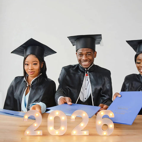 Graduates with diplomas behind 2026 Graduation Decorations LED Marquee Numbers Light Up 2026 For Class Of 2026 Party Vibe
