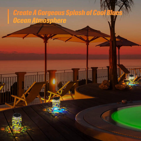 Three Piece Solar Powered Mosaic Lights Set illuminating a patio area at sunset with chairs and umbrellas, ocean view in background.