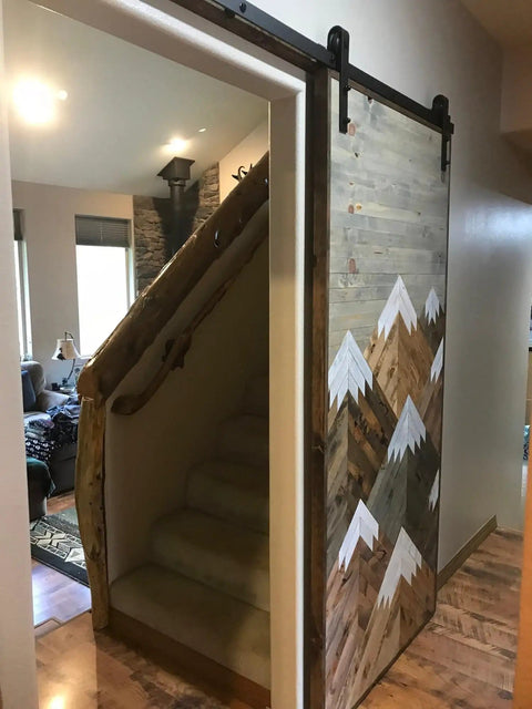 Space Saving Rustic Wood Mountains Sliding Barn Door For Home with mountain design, used as room divider, view showing staircase entry.