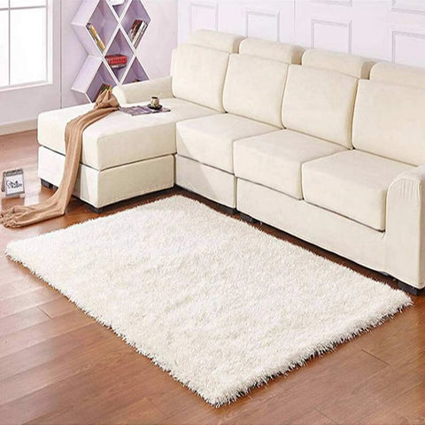 Modern living room with white sectional sofa, fluffy white rug on wooden floor, geometric shelf