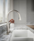 Top Shelf Pull Down Kitchen Sink Faucet With Smooth Glide Retractable Hose And Dual Function Sweep Sprayhead Built Tough For Lightning Fast Cleanup In Classic Vibrant Stainless Finish installed on a modern countertop with a white sink.