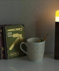 Brownstone Torch Lamp 11.5 Inch LED Night Light With USB Charging Port next to books and cup on desk setup.