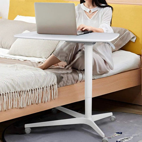 Slick Mobile Laptop Desk With Adjustable Height And No Sweat Rolling Casters Nifty Bedside Workstation in use beside a bed.