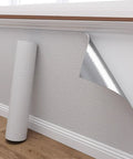 Peel And Stick Thermal Wall Covering With 3mm Foam Backing For Damp Rooms Easy Breezy Application gray roll partially applied to wall.