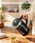 Person pouring water from Electric Tea Kettle With Temperature Control And Glass Body For Tea And Coffee into a glass mug.