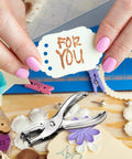 Close-up of 24 Pack 1/4 Inch Single Hole Punch Set Metal Paper Puncher used for card making, surrounded by crafts and gift tag 'For You'