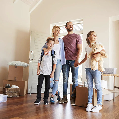Family standing in a new home surrounded by moving boxes.