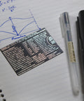 Mini Physics Multi Tool Ruler With Protractor And Compass Stainless Steel Gadget on notebook beside pen and calculator