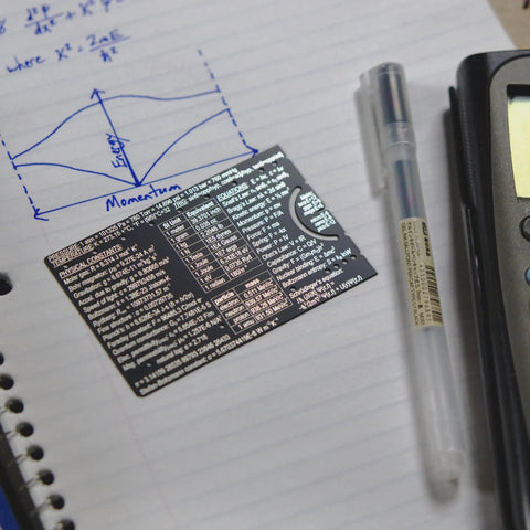 Mini Physics Multi Tool Ruler With Protractor And Compass Stainless Steel Gadget on notebook beside pen and calculator