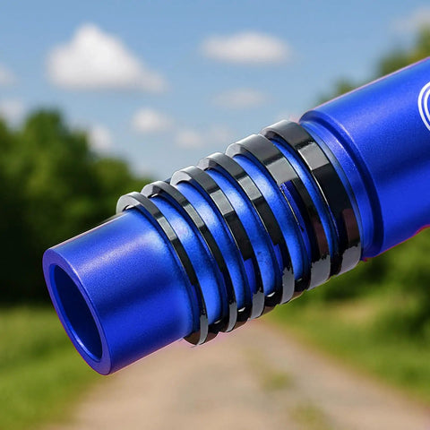 Blue aluminum bicycle headset spacers in various sizes for 1 1/8 inch stems, shown outdoors on a background of trees and sky.