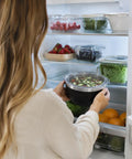Person placing Hella Solid 32 Oz Double Wall Vacuum Insulated Stainless Steel Bowl With Tight Seal Silicone Lid in a fridge.