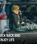 Person sitting in car trunk using a laptop powered by Venture 75 Portable Power Bank With 19200mAh Battery, outdoors in winter.