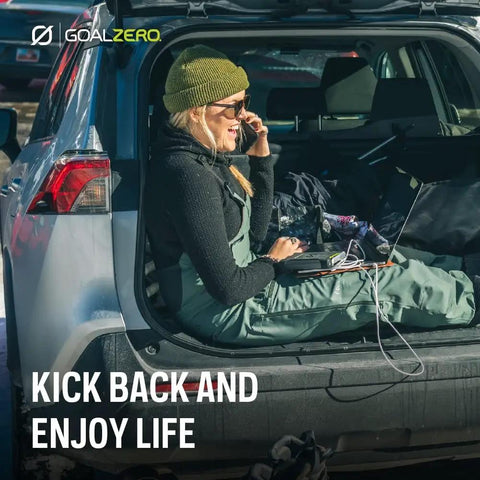 Person sitting in car trunk using a laptop powered by Venture 75 Portable Power Bank With 19200mAh Battery, outdoors in winter.