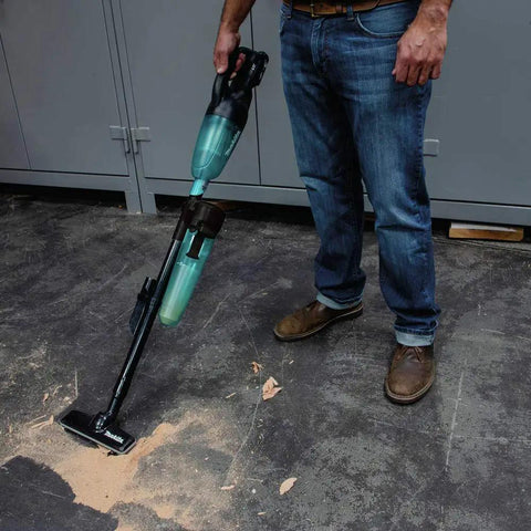 Man using Cyclonic Vacuum Attachment For 18v And 12v Cordless Handheld Tools on dusty workshop floor.