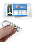 Hand holding component of 38 Piece Hitch Pin Clip Set With Five Sizes For Trailer And Tractor Applications Including Hair Pins R Clips Retaining Pins Spring Clips And Dolly Pin Replacement Kit By Yoliko, product box in background.