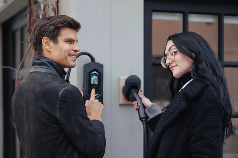 Two people using the Go-To Portable Level 2 EV Charger With 40 Amp Output, 25ft Cable, 120V To 240V NEMA 14-50, Outdoor EVSE With LED Display.