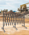 Straight Up Heavy Duty Expandable Metal Barrier On Wheels, Adjustable Retractable Safety Fence For Crowd Control, Rolling Traffic Gate With Locking Casters, Foldable Industrial Yard Barrier, Coffee Brown on a construction site.