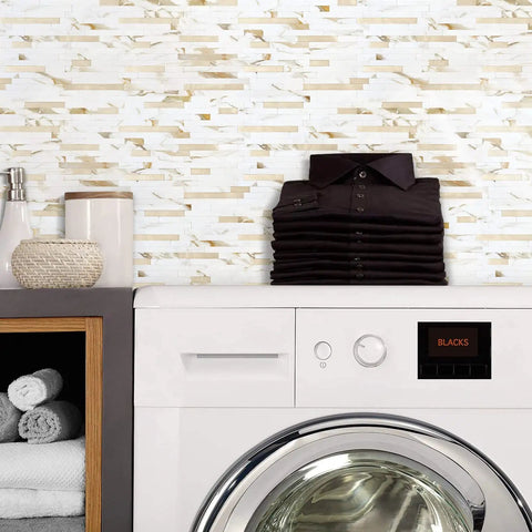 Laundry room with Peel And Stick Backsplash Tiles Marble Calacatta With Metal Gold Finish behind a white washing machine.