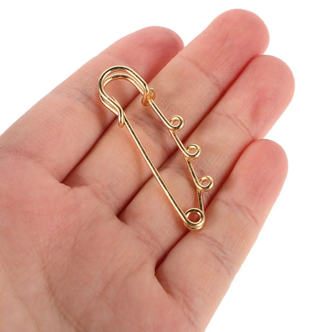 Top Shelf Loop Safety Pin Brooch Set Of Twenty Pieces Electroplated In Rich Golden Tone For Sweaters Coats And Jackets Featuring Reliable Non Slip Clasp to secure garments, held in a hand.