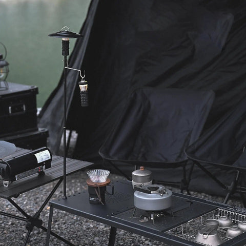 Collapsible Lantern Stand For Camping And Backyard with aluminum hook, ground stakes and lantern, next to camping setup.