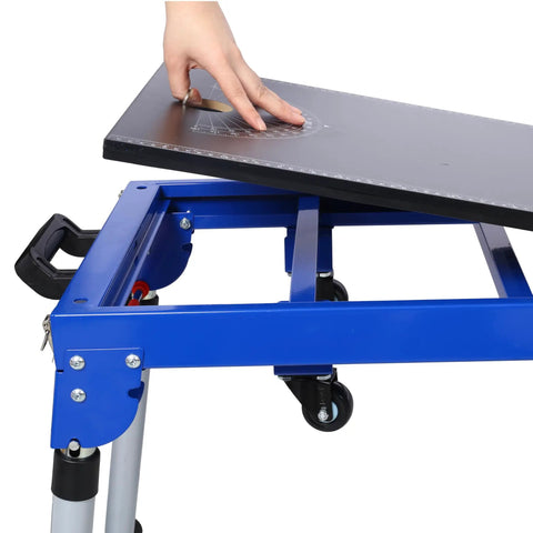 Built Tough Miter Saw Stand And Five In One Folding Portable Workbench With Telescoping Height Legs And Smooth Roll Caster Wheels For Woodworking And Masonry In Blue, showing user adjusting the angle on the surface.