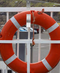 Sturdy Iron Sea Life Buoy Ring Hanger Rack With Hook For Pool Safety Gear Outdoor Use Heavy Duty Metal Bracket on a fence with an orange lifebuoy.