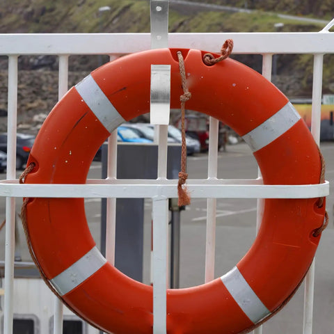 Sturdy Iron Sea Life Buoy Ring Hanger Rack With Hook For Pool Safety Gear Outdoor Use Heavy Duty Metal Bracket on a fence with an orange lifebuoy.