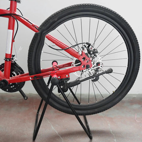 Garage Ready Vertical Triangle Bike Stand For Indoor Parking, metal and black, holding a bike by the rear wheel in a garage.