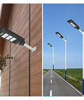 Badass Heavy Duty 350W Solar Floodlight With Photocensor And Motion Sensor mounted on a wall and poles along a road.