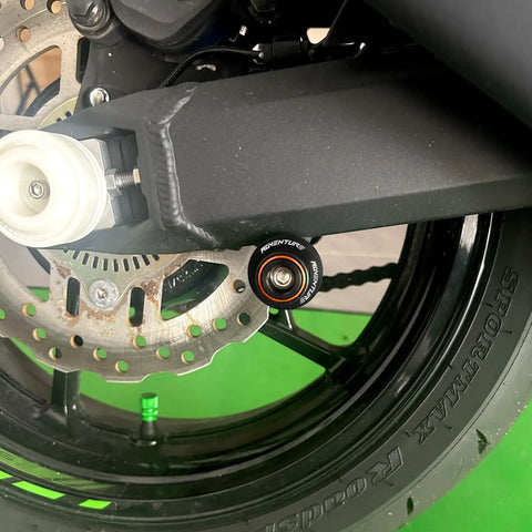 Close-up of Orange Swingarm Spools Sliders And Rear Stand Screws Kit for KTM Adventure and Duke motorcycles installed on swingarm.
