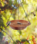Outdoor Hanging Bird Bath In Antique Copper Metal With 17 Inch Rust Proof Black Chains, surrounded by birds and foliage.
